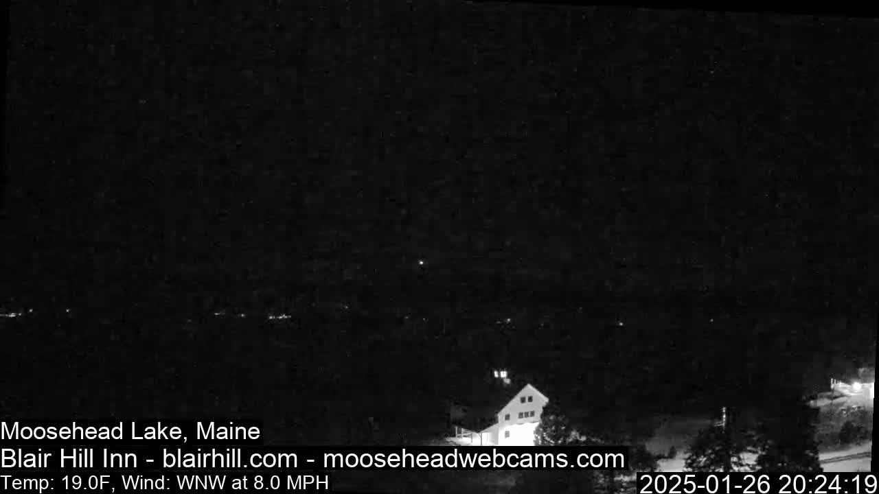 A nighttime view of a lake and a building, under a dark sky with a WNW wind at 8.0 mph and a temperature of 19°F.