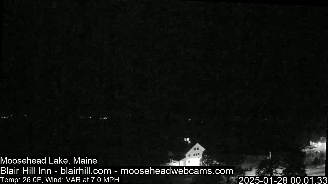 A nighttime, low-light view of a building and surrounding area with a 26°F temperature and a 7.0 mph variable wind.