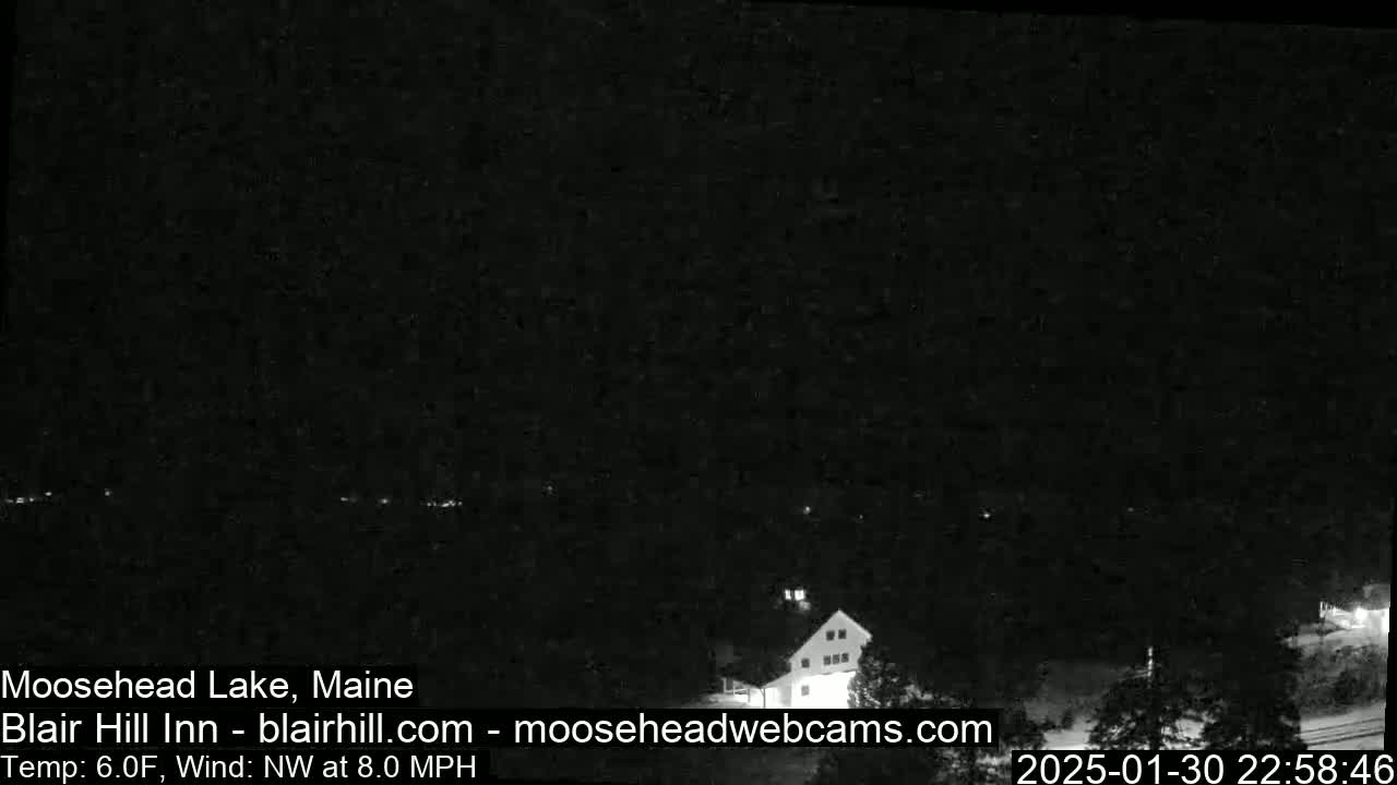 A dark, nighttime view of a lake and a building with a northwest wind at 8.0 mph and a temperature of 6.0°F.