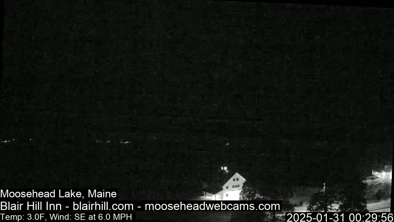 A dark nighttime scene shows a building near a body of water under a clear sky, with a southeast wind at 6.0 mph and a temperature of 3.0°F.