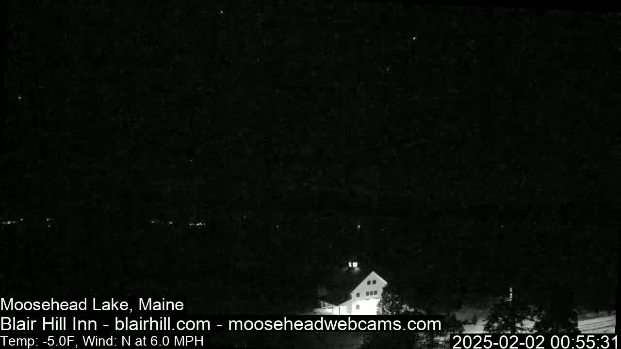 A nighttime, long shot of a building in a dark, snowy or icy landscape with a north wind at 6.0 mph and a temperature of -5.0°F.
