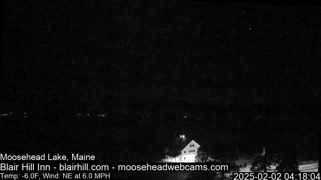 A dark nighttime image shows a building lit from within, with a northeast wind at 6.0 mph and a temperature of -6.0°F.