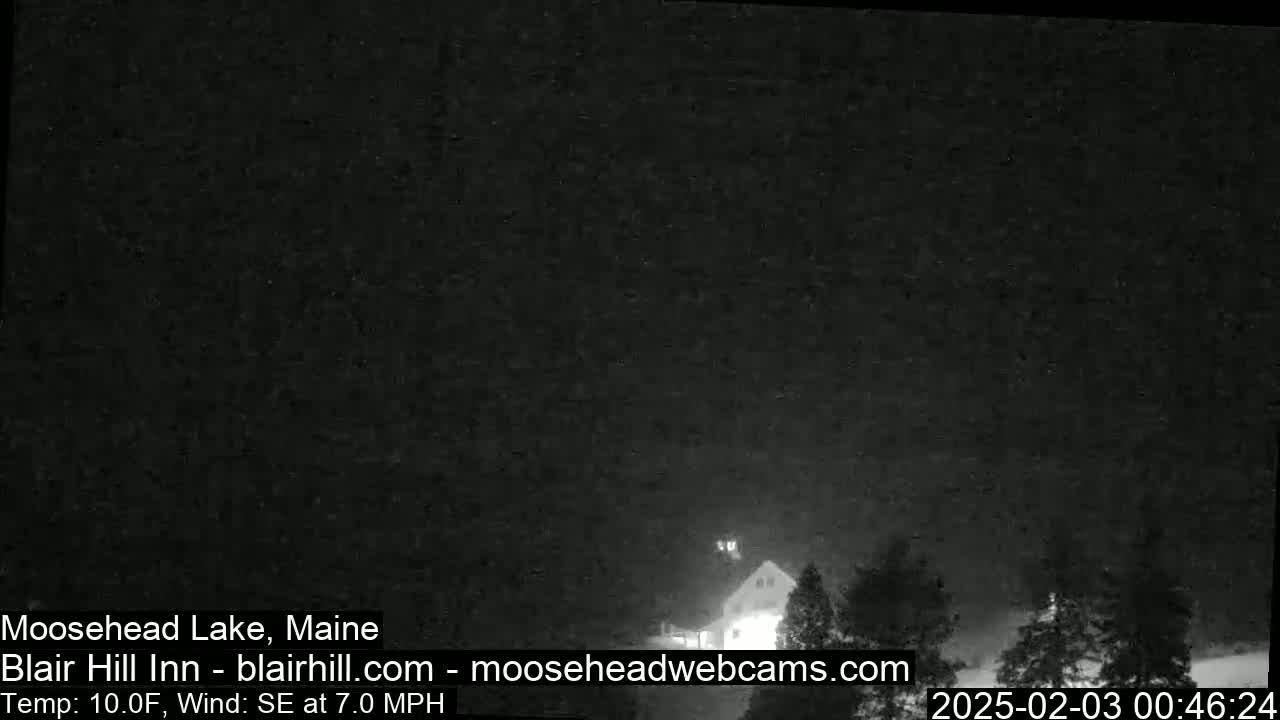 A nighttime, low-light view of a building and trees under a dark sky with a southeast wind at 7 mph and a temperature of 10°F.