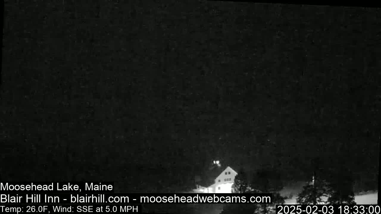 A dark, nighttime scene shows a building partially visible through trees under a clear, dark sky with a 26°F temperature and a 5 mph SSE wind.