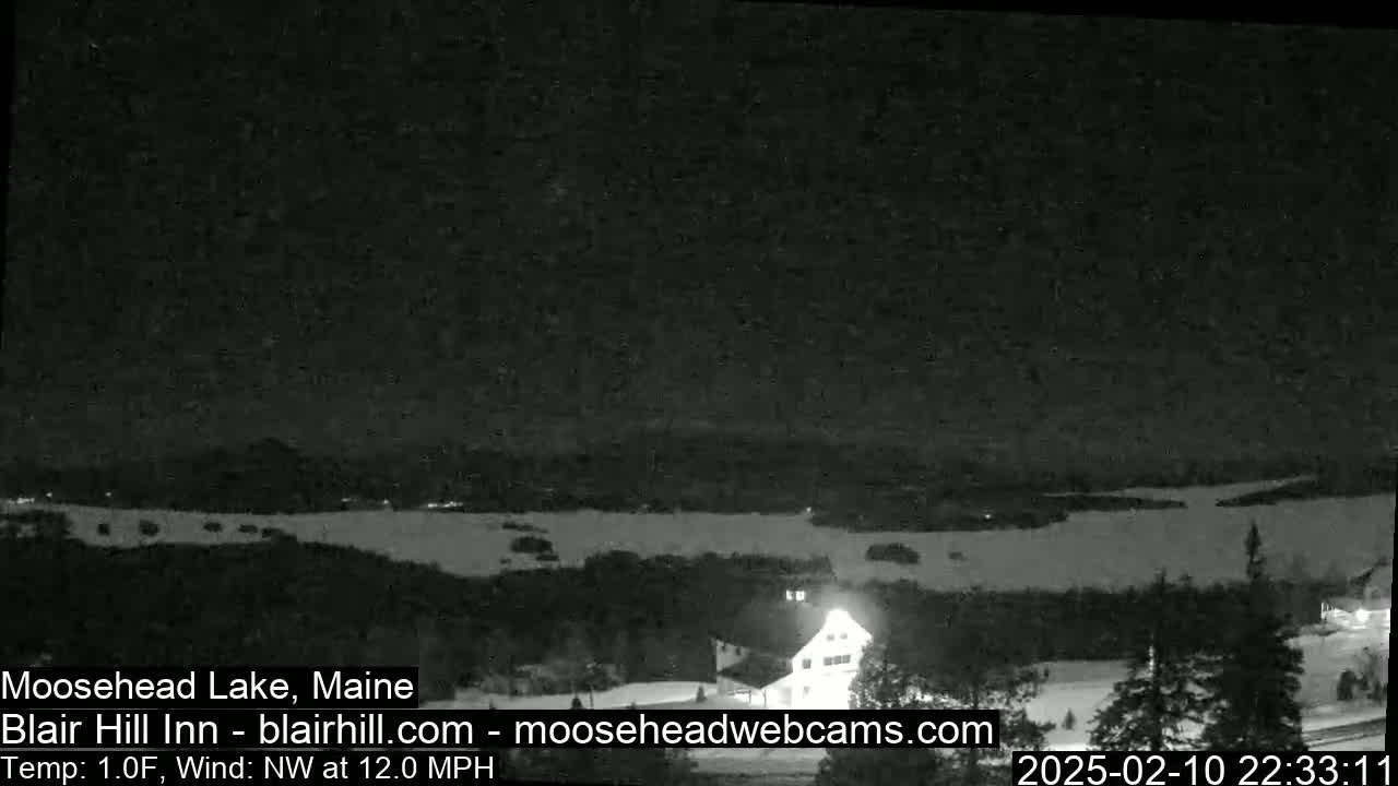 A nighttime view of a lake and a building, with a northwest wind at 12 mph and a temperature of 1 degree Fahrenheit.