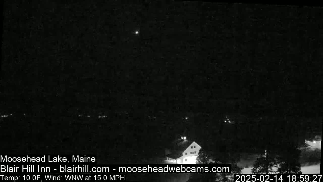 A nighttime, low-light view of a building and surrounding area with a 15 mph wind from the west-northwest and a temperature of 10°F.