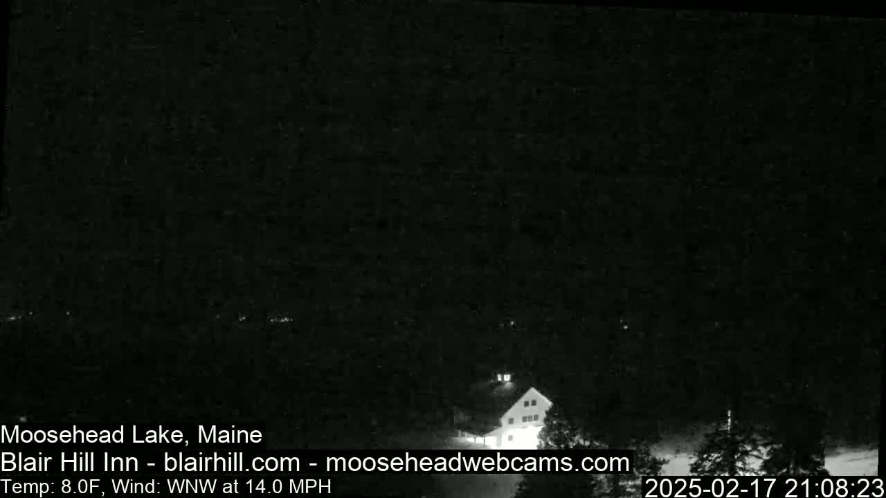 A dark, nighttime view of a building, possibly a lodge, with a WNW wind at 14.0 mph and a temperature of 8.0°F.