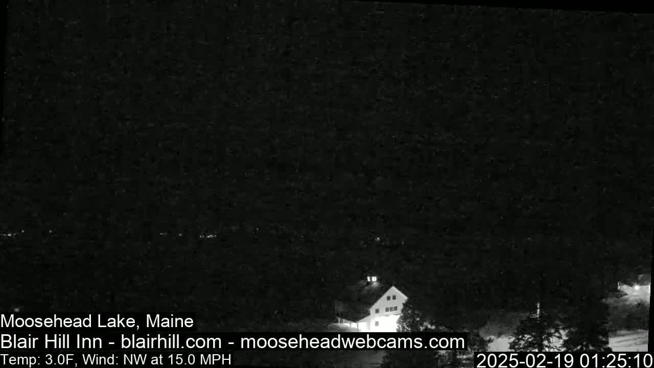 A dark nighttime scene shows a building and trees under a dark sky with a northwest wind at 15 mph and a temperature of 3 degrees Fahrenheit.