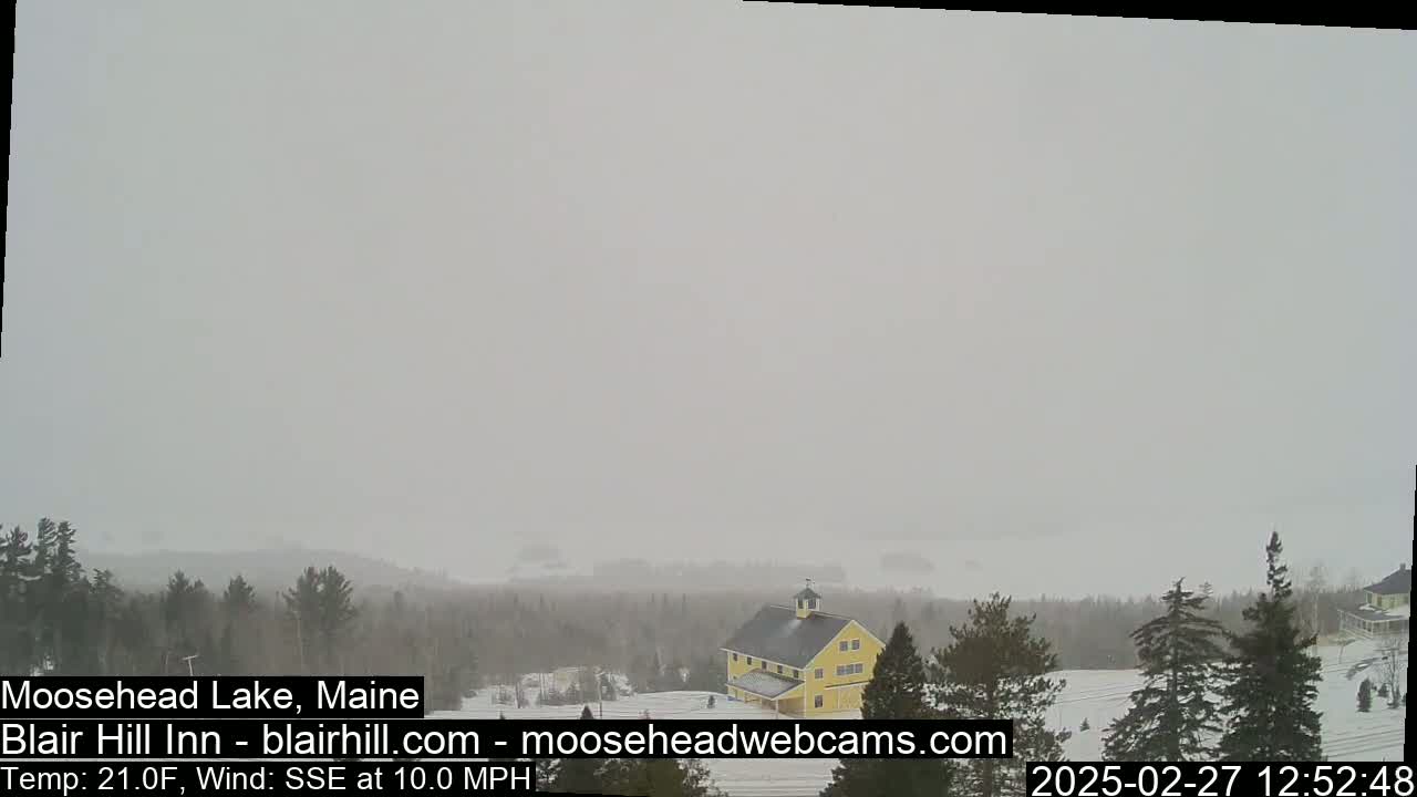 A yellow barn is visible in a snowy landscape with a mostly overcast sky.