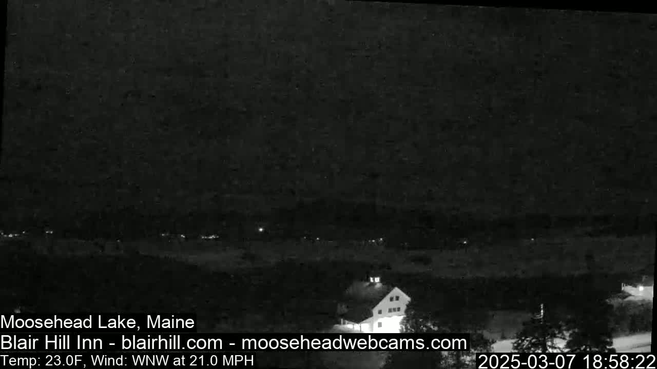 A dark nighttime view of a lake and a building, with a strong wind blowing from the west-northwest.