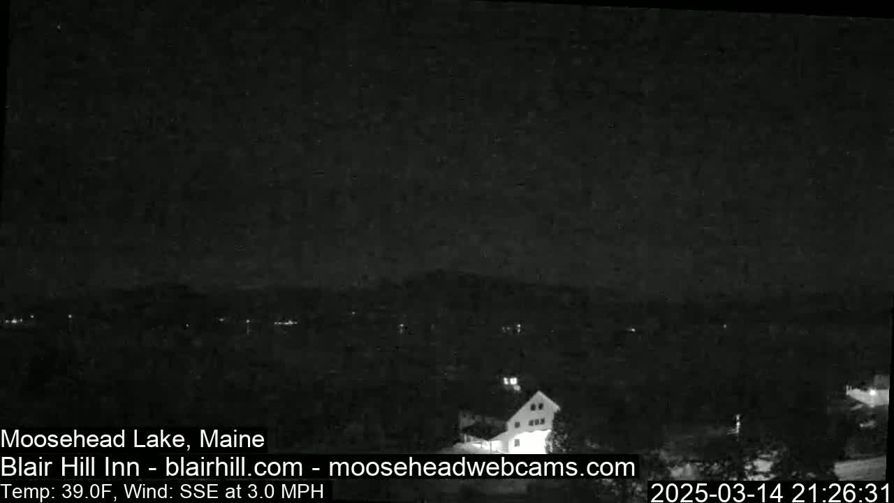 A nighttime view of a lake and buildings under a dark, clear sky with a light wind.