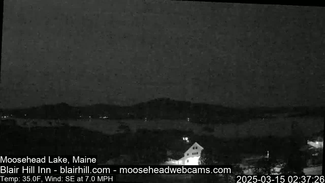 A nighttime, low-light view of a lake and distant hills under a dark sky with a 35°F temperature and a 7 mph southeasterly wind.