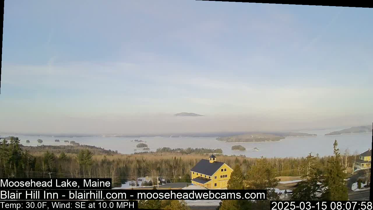 A mostly clear, cold day with a southeast wind shows a frozen lake with islands and a yellow barn from a high vantage point.