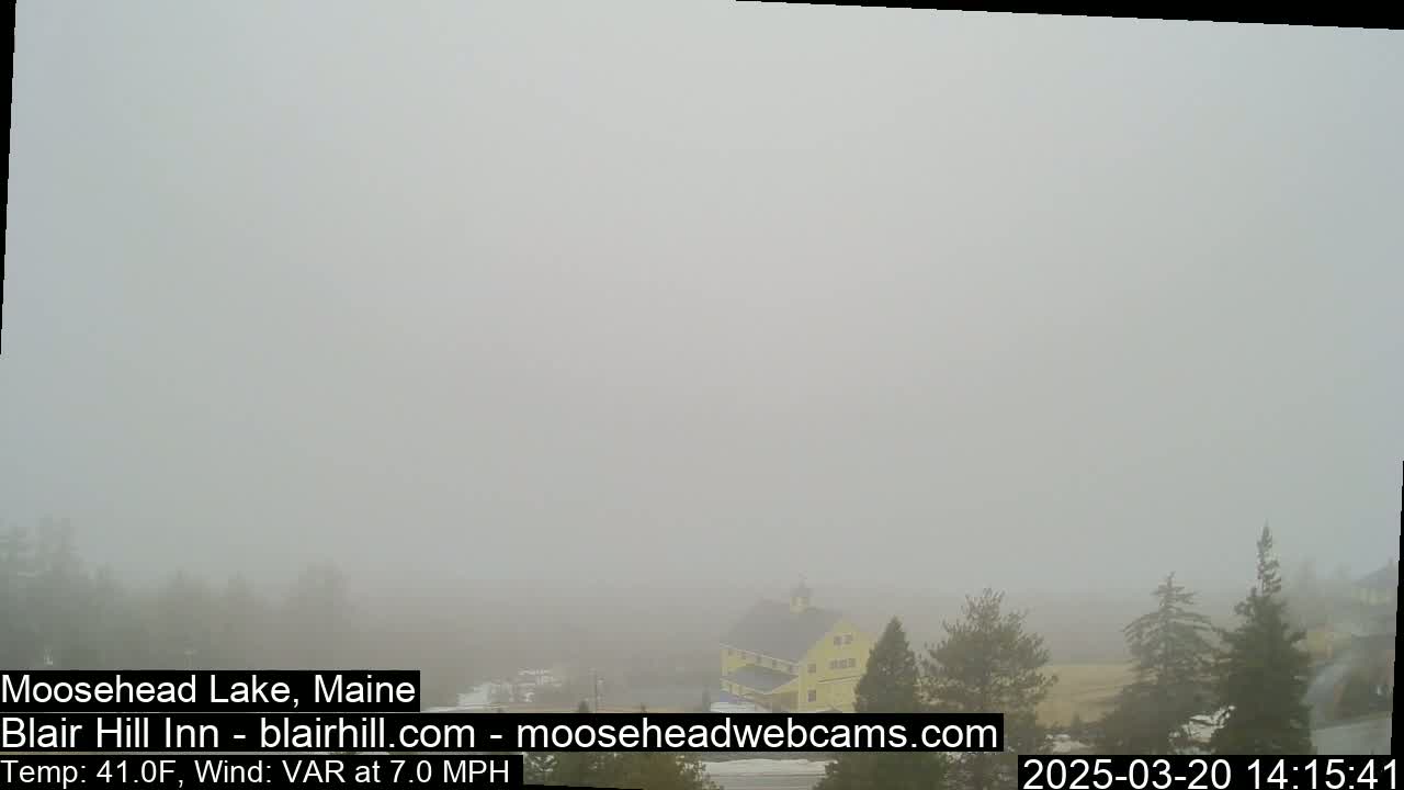 A thick fog obscures a landscape featuring a yellow barn and evergreen trees.