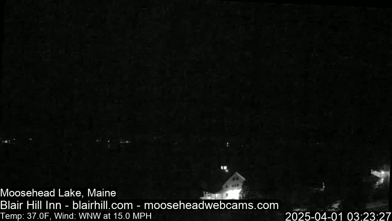 A nighttime, low-light view of a lake and a building with a 37°F temperature and a 15 mph wind from the west-northwest.