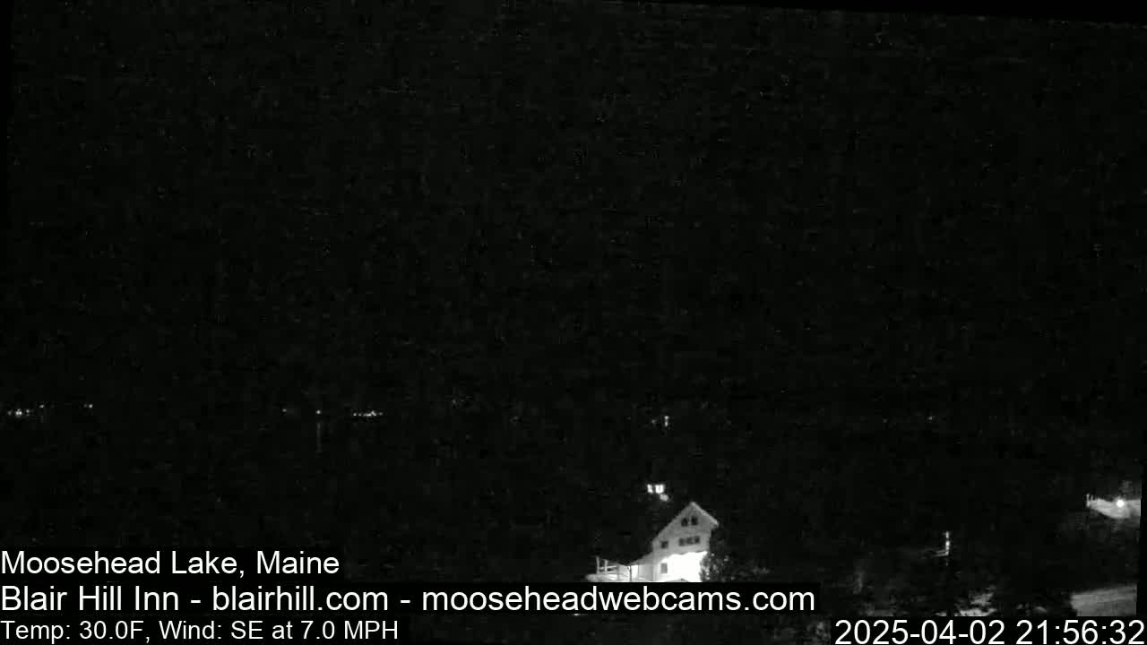 A nighttime, low-light view of a lake and a building, with a southeast wind at 7 mph and a temperature of 30°F.