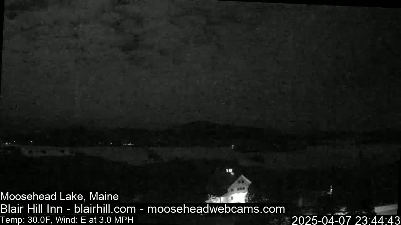 A nighttime, low-light view of a lake and a building under a cloudy sky with an east wind at 3.0 mph and a temperature of 30°F.