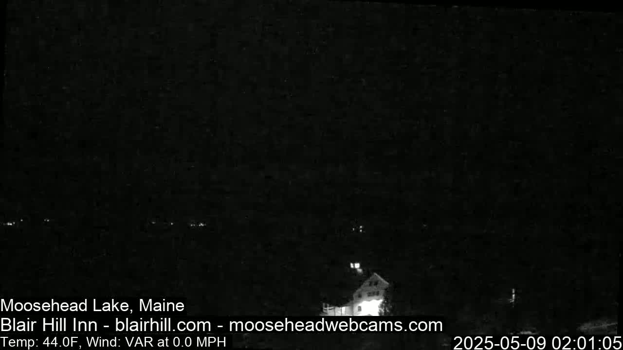 A dark nighttime scene shows a building and a few distant lights, with calm, 44°F weather.