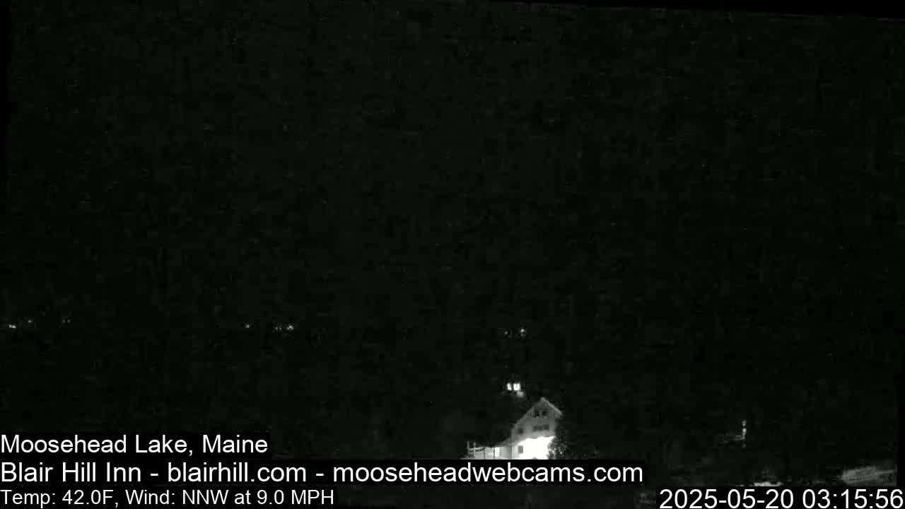 A dark nighttime scene shows a building faintly illuminated, with a 42°F temperature and a 9 mph north-northwest wind.