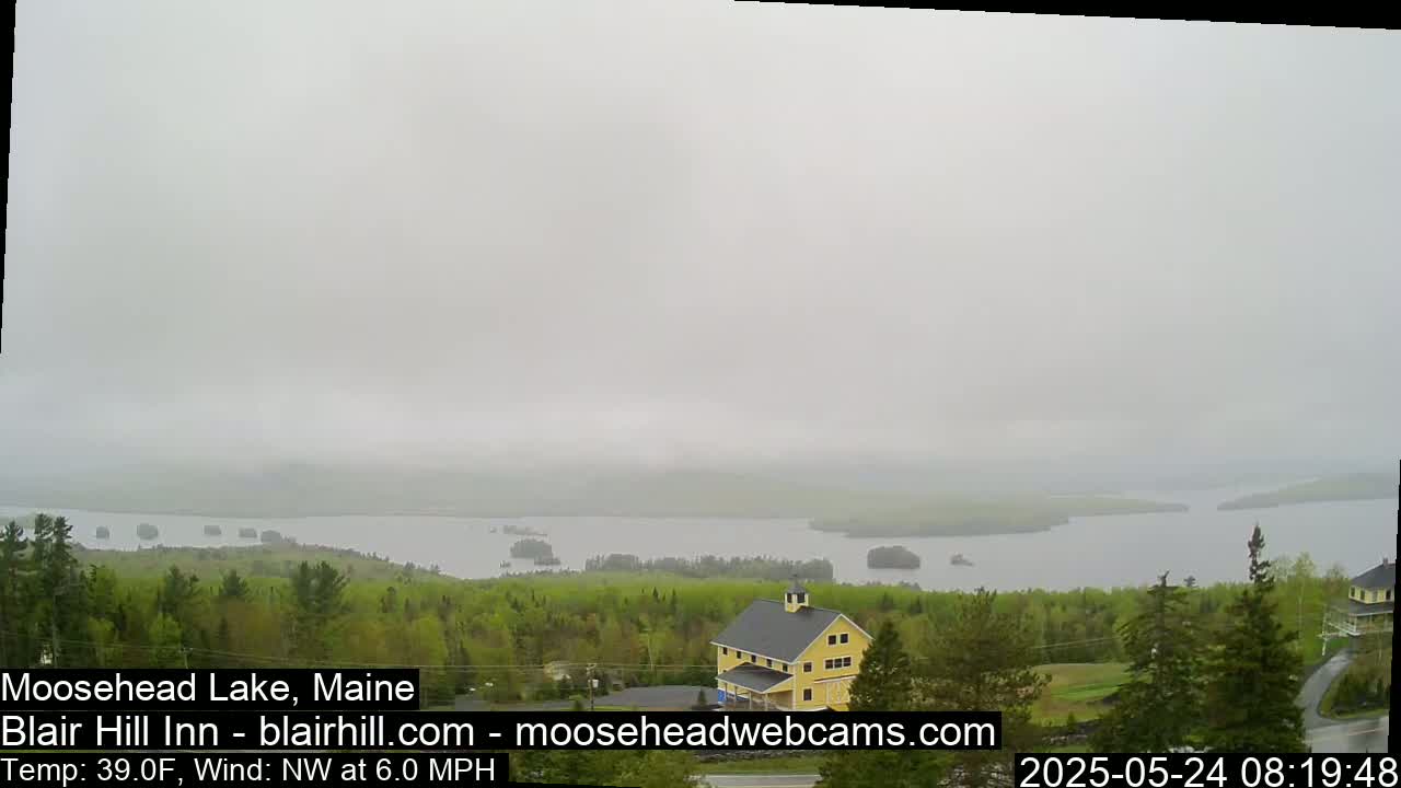 A hazy, gray day reveals a view of a lake with islands, a yellow building, and green trees.