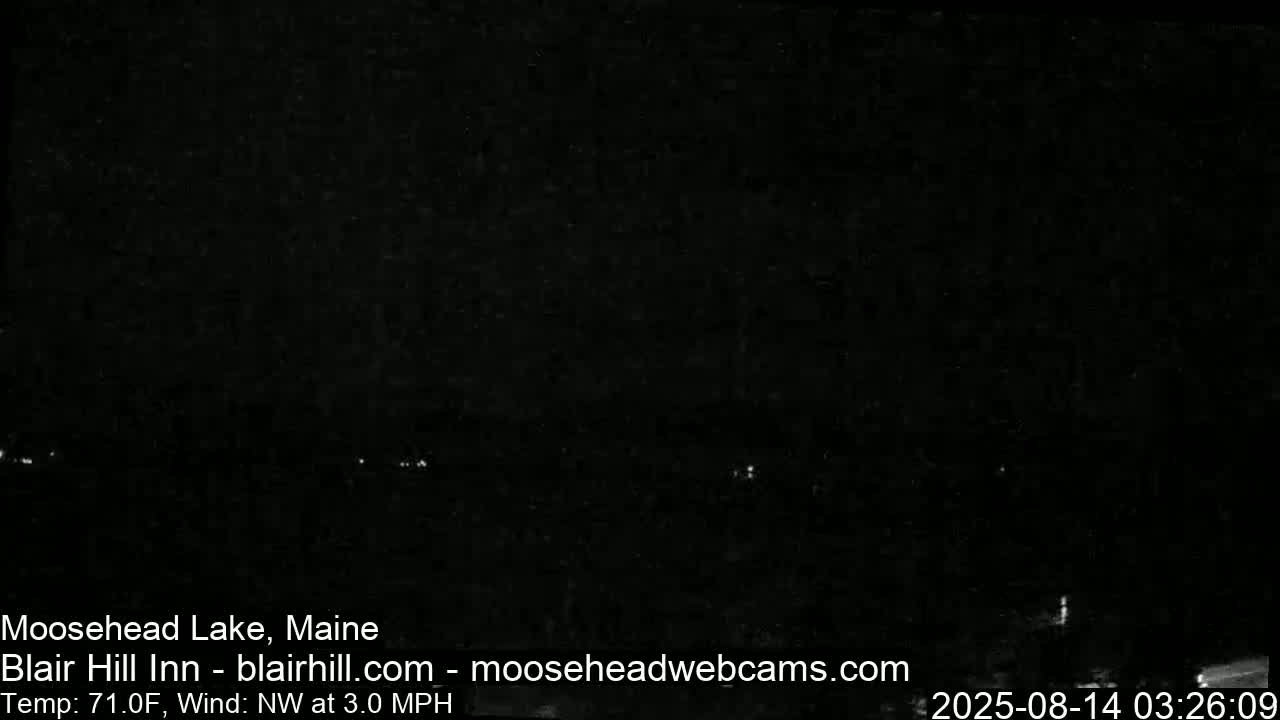 A nighttime long shot shows a dark landscape with a few distant lights under a clear sky, with a temperature of 71°F and a northwest wind at 3.0 mph.