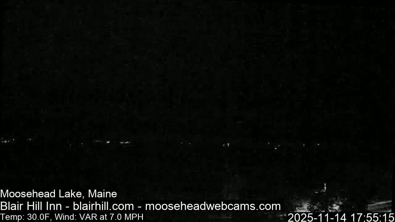 The image displays a dark, clear night with a faint, scattered line of distant lights stretching horizontally across what appears to be a body of water or land beneath an unlit sky.