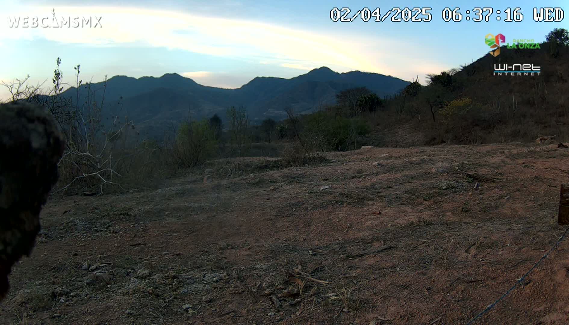 A mostly barren, dusty landscape under a twilight sky shows distant mountains.