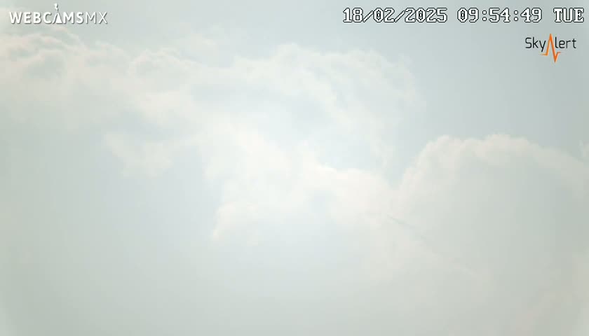 A mostly cloudy sky is visible, with scattered cumulus clouds under a pale blue sky.