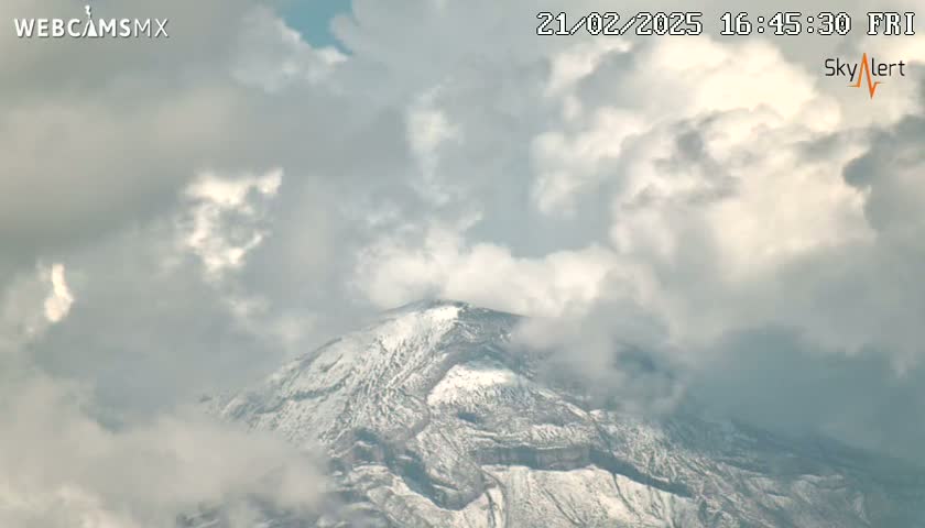 A snow-capped mountain is partially obscured by a cloudy sky.