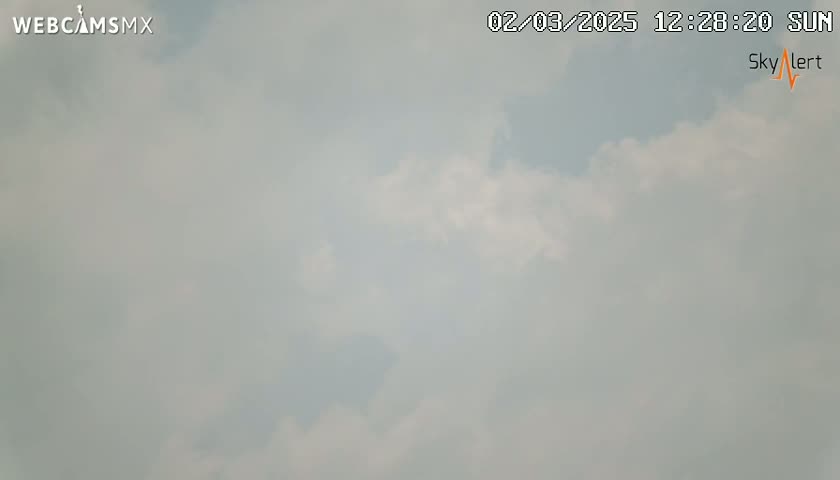 A mostly cloudy sky is visible on a hazy, sunny day.