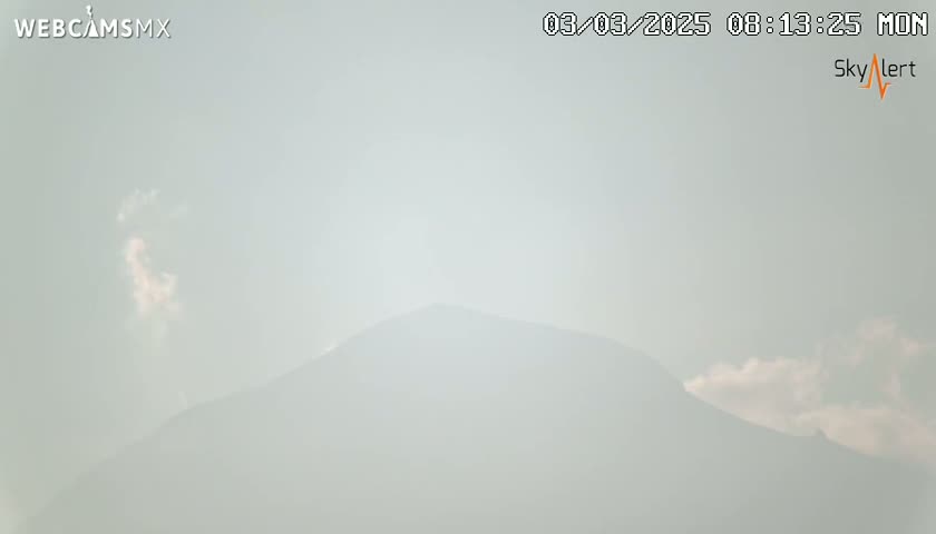 A hazy, sunlit mountain is visible in the distance under a mostly clear sky.