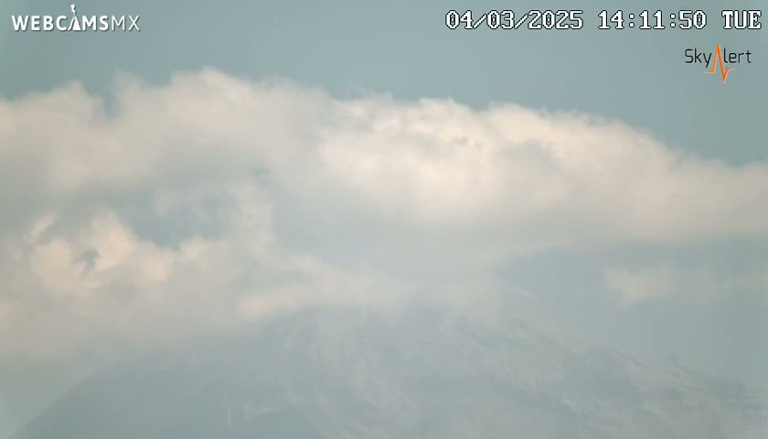 A partly cloudy sky obscures a distant, hazy mountain range.