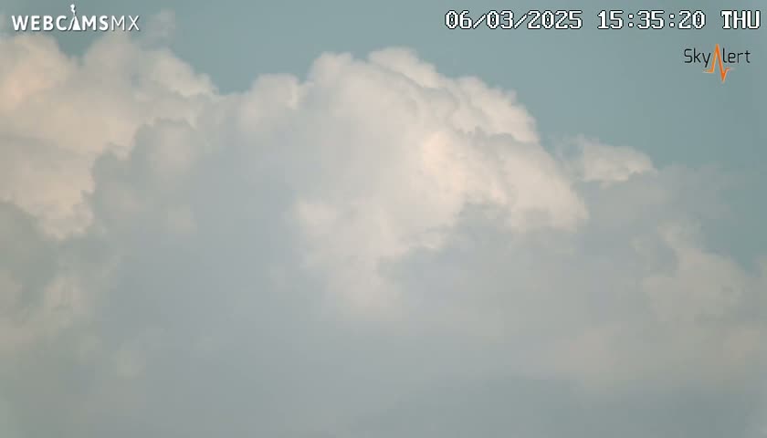 A mostly cloudy sky with puffy white and gray clouds dominates the view.