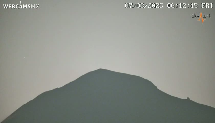 A dark, silhouetted mountain is visible against a pale, hazy sky.