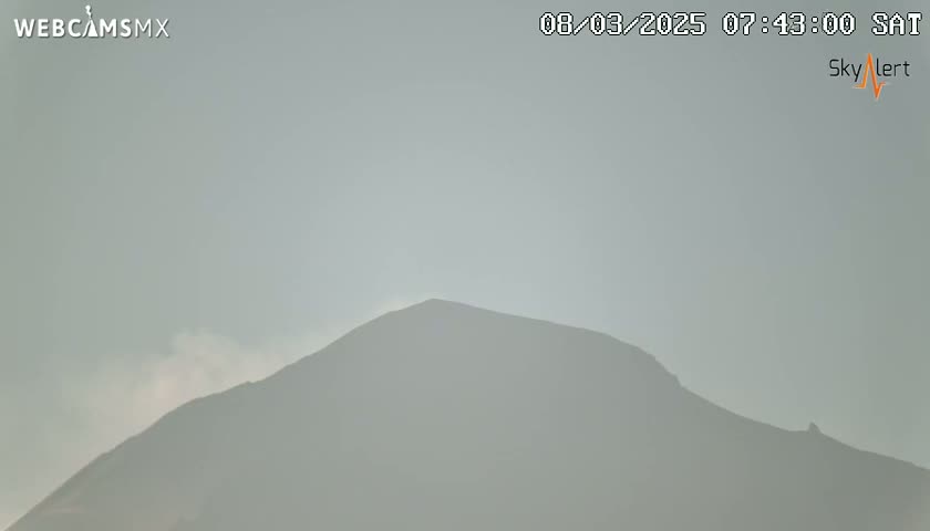 A hazy, light-grey mountain is visible under a mostly clear sky.