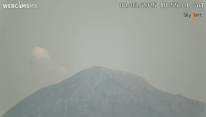 A hazy, overcast sky obscures a view of a large, dark mountain.