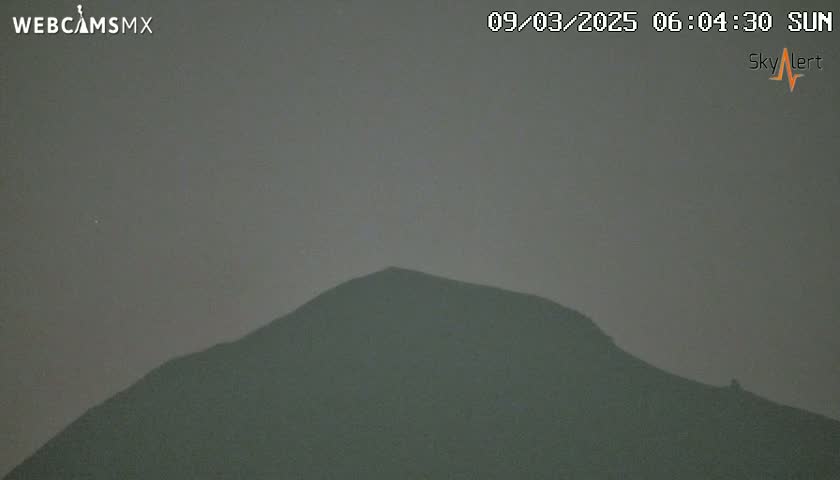 A dark, hazy sky obscures a silhouetted mountain range.