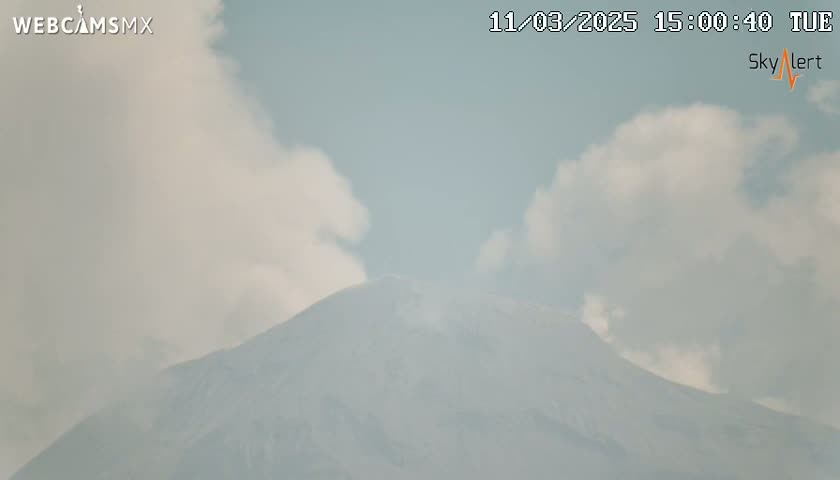 A partly cloudy sky hangs over a large, hazy mountain.