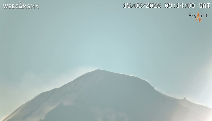 A hazy, light-blue sky is visible above a dark mountain range.