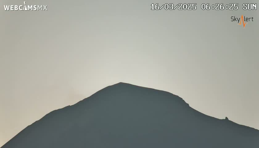 A dark, silhouetted mountain is visible against a pale, overcast sky.