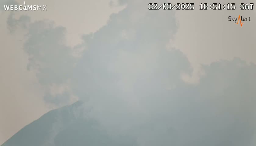 A hazy, overcast sky partially obscures a mountain range in the distance.