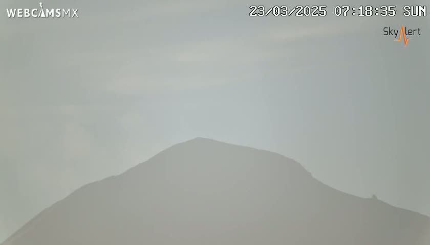 A hazy, overcast sky obscures a distant mountain range on a sunny morning.