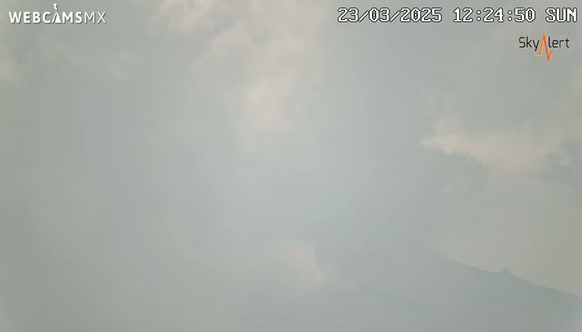 A hazy, cloudy sky obscures a distant mountain range under sunny conditions.