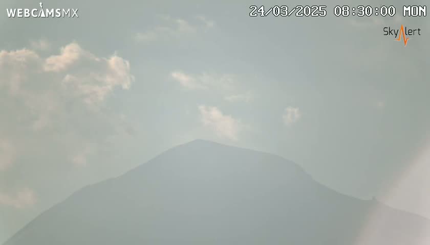 A hazy, partly cloudy sky overlooks a distant, indistinct mountain.