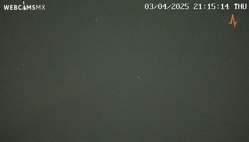A nighttime outdoor image shows a dark, mostly clear sky with a few faint lights visible.