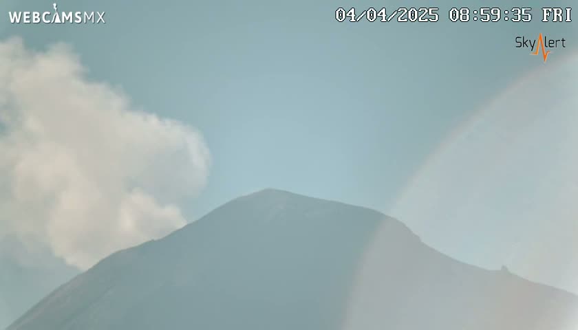 A hazy mountain is visible under a partly cloudy sky.