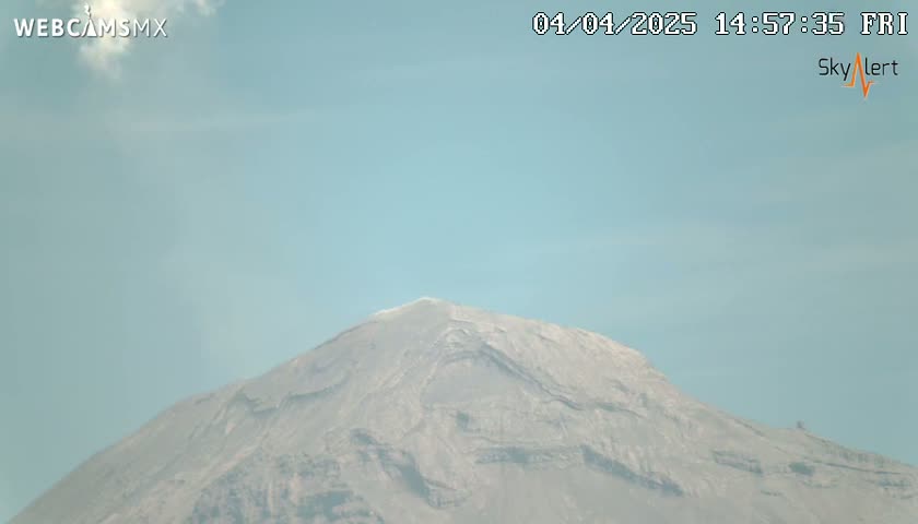 A large, gray mountain is visible under a clear, light-blue sky.