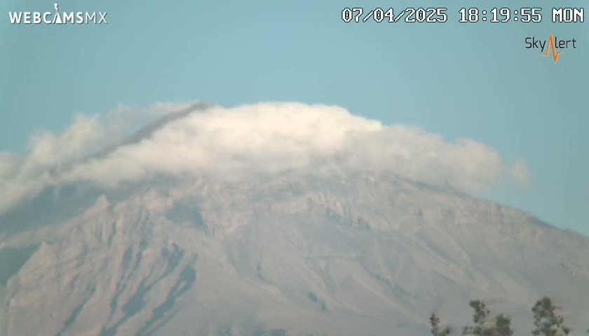 A partially cloud-covered mountain is visible under a clear, light-blue sky.