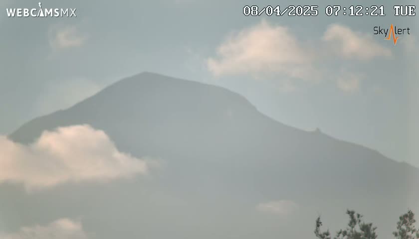 A hazy, partly cloudy day reveals a mountain shrouded in mist.