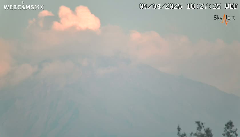 A hazy, cloudy sky partially obscures a distant mountain range.